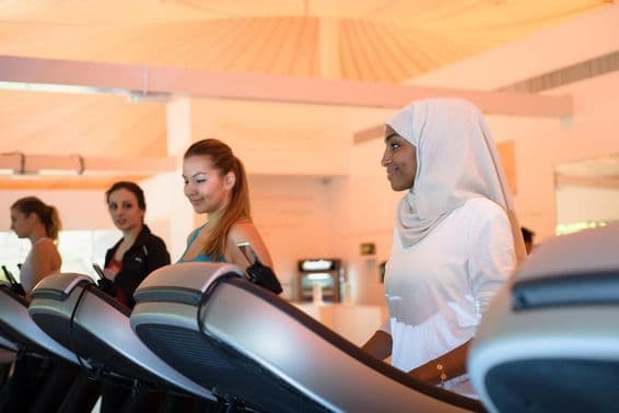 Gruppe von Frauen auf Laufbändern im Fitnessstudio.