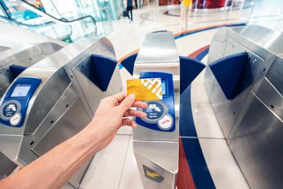 Ein männlicher Passagier verwendet eine goldene Nol-Karte in der Dubai Metro, um ein Drehkreuz zu passieren und im ersten Wagen zu reisen.