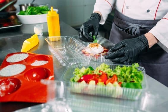 Der Koch bereitet Essen im Restaurant zu und verpackt es in Einwegbehältern.