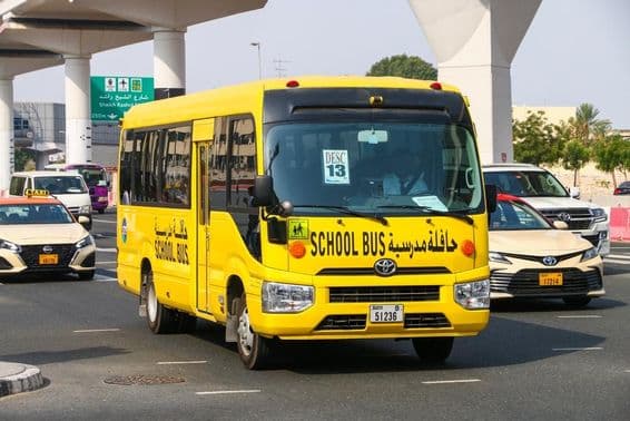 Schulbus Toyota Coaster auf einer Stadtstraße.