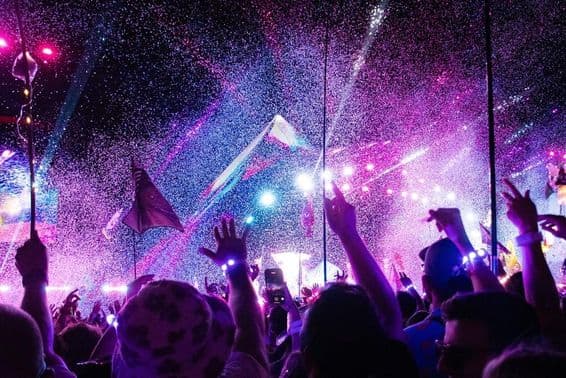 Musikfestival, Bühne, feiernde Menge mit erhobenen Händen.