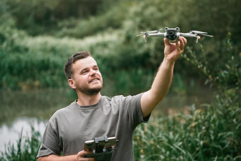 Drohnenlehrer mit Drohne in der Hand während eines Outdoor-Kurses.
