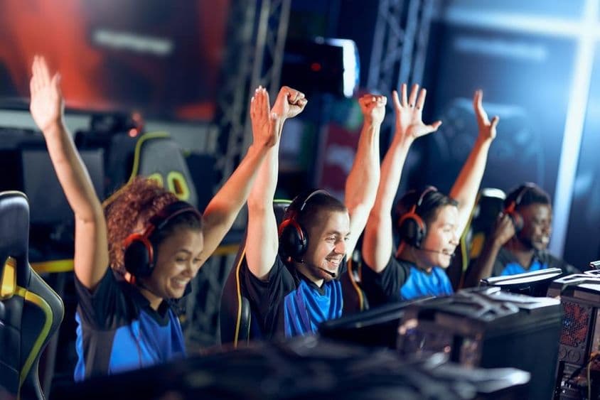 Ein jubelndes Team von Cybersport-Spielern feiert Erfolg während eines Esports-Wettbewerbs.