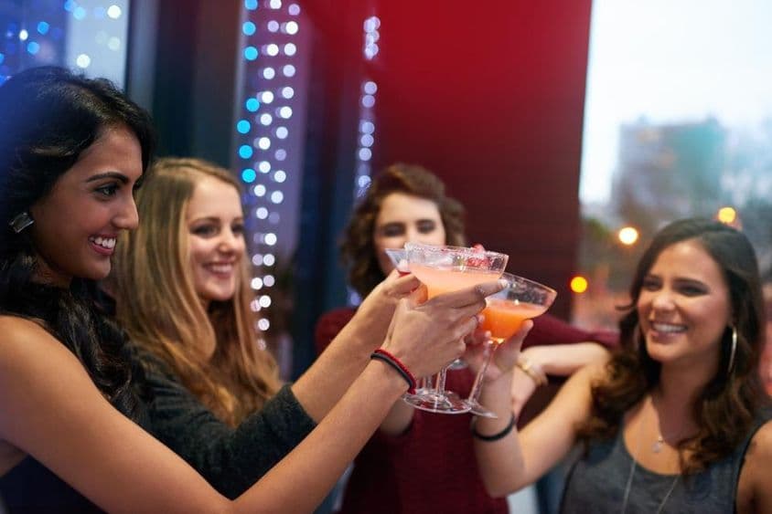 Mädchen stoßen mit Getränken in einer Cocktailbar an.