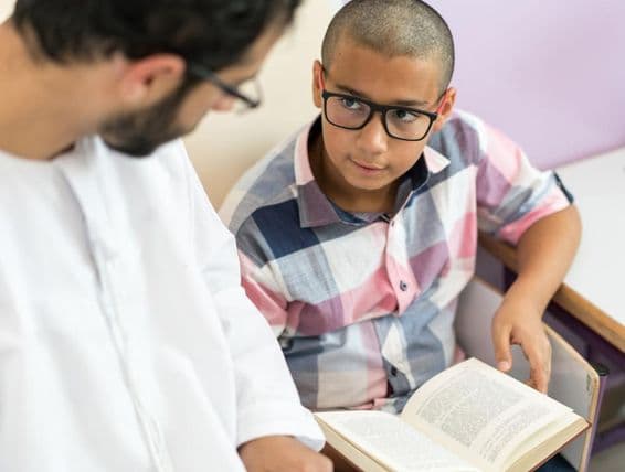 Junger arabischer Lehrer lernt mit einem Schuljungen.