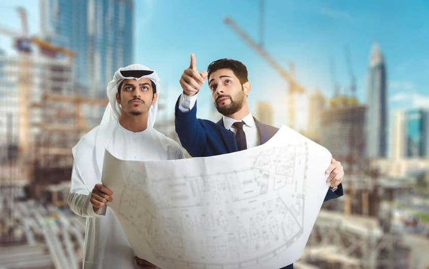 Architekt erklärt den Bauplan arabischen Bauarbeitern