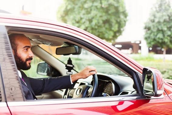 Junger Geschäftsmann fährt ein rotes Mietauto.