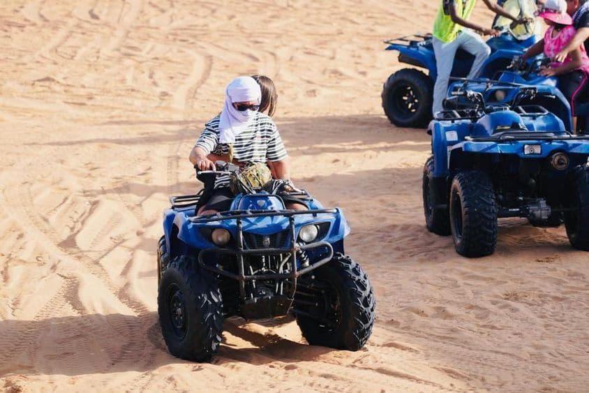 Junges Paar fährt ein Quad in der Wüste von Dubai.