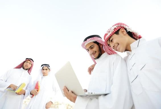 Glückliche arabische Studenten sehen sich Bildungsinhalte auf einem Laptop an.