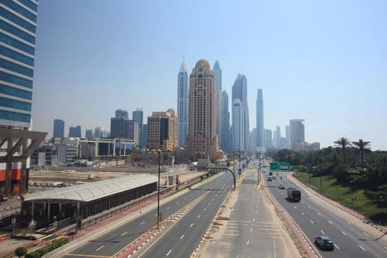 Straßenszene in Dubai mit Wolkenkratzern und Straßenbahn im Hintergrund.