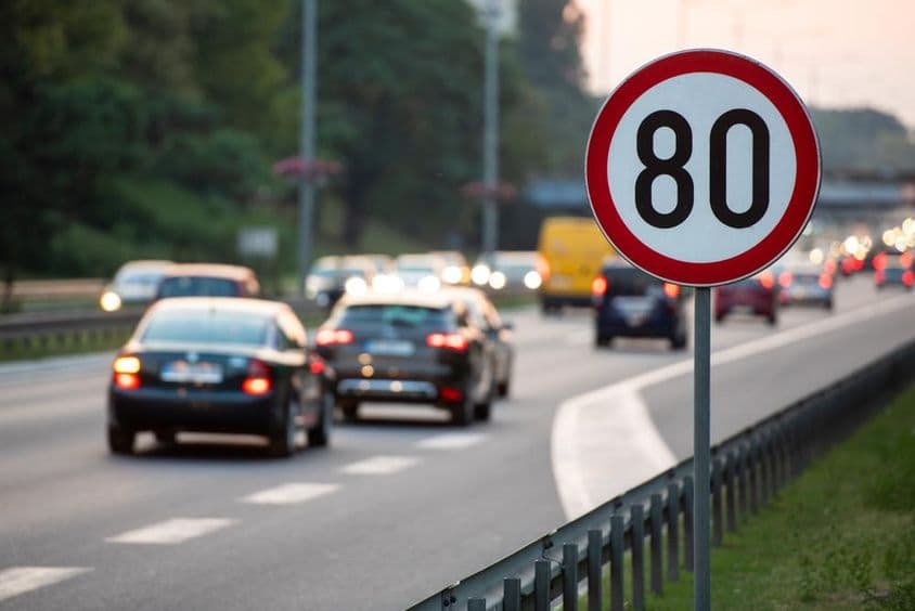 80 km/h Geschwindigkeitsbegrenzungsschild auf einer stark befahrenen Straße.