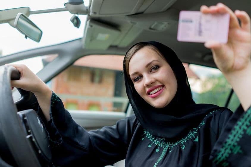 Muslimische Frau fährt Auto, hält Führerschein.