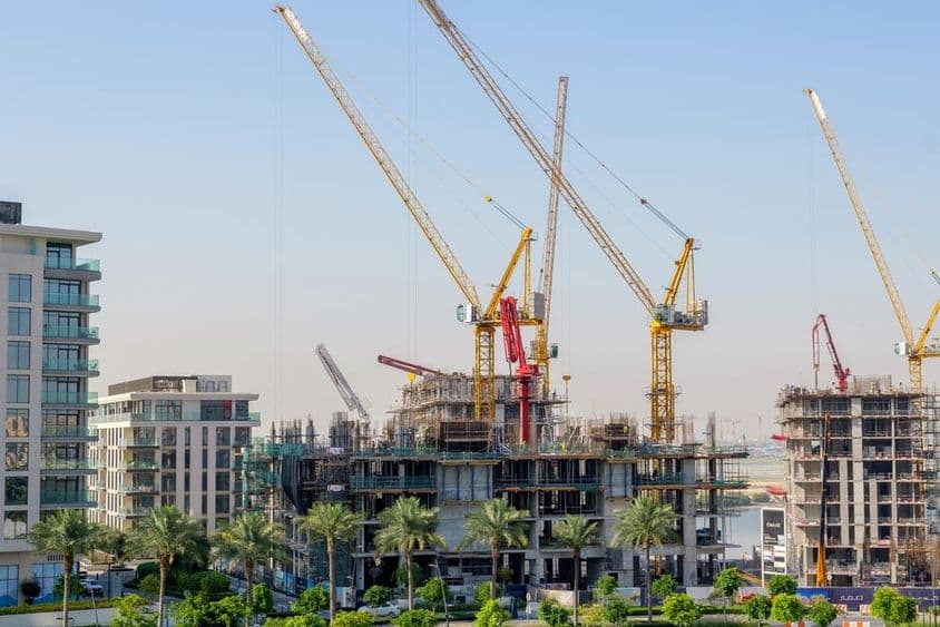 Wohngebäude im Bau mit Kränen im Hafen von Dubai Creek.