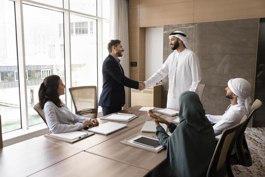 Arabische und europäische Geschäftsleute schütteln sich bei einem Teamtreffen die Hände, Unternehmensdiskussion.