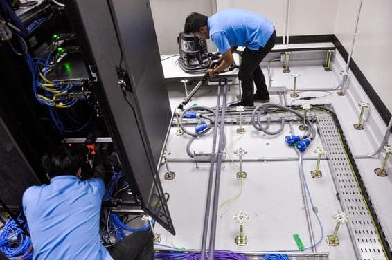 Arbeiter bauen einen Serverraum mit Doppelboden und Schrankanlagen.