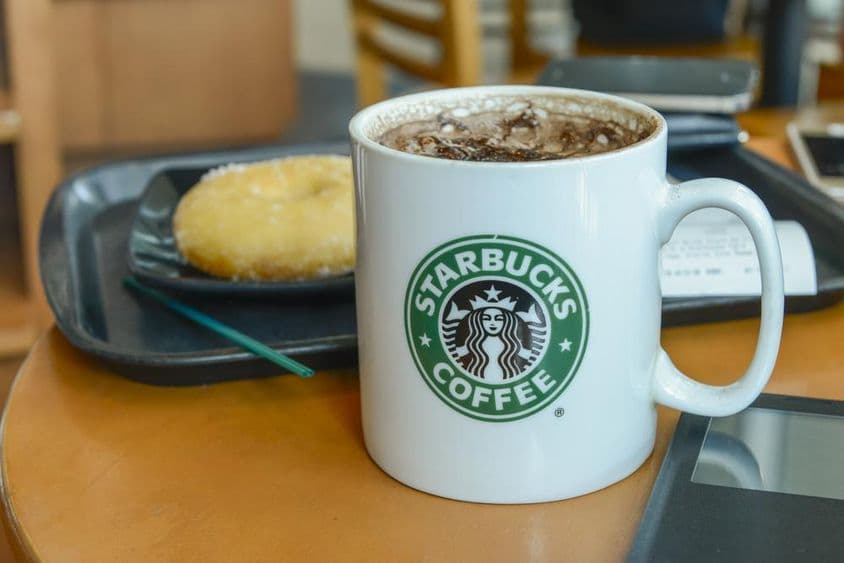 Kakao-Cappuccino in einer heißen, dampfenden Tasse in einem Starbucks-Café.