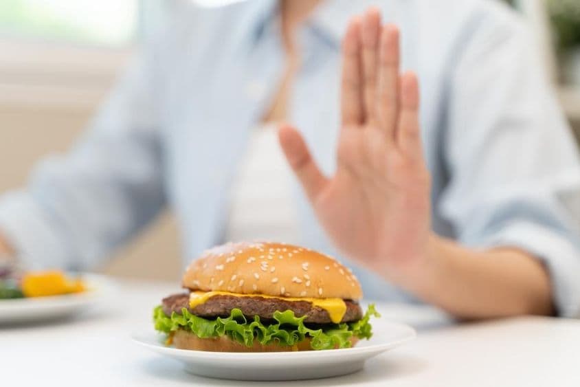 Eine Frau lehnt einen fettigen Fast-Food-Hamburger ab.