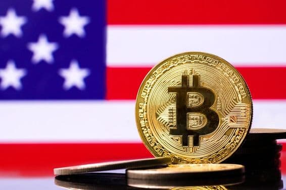Goldene Bitcoin-Münze mit der US-Flagge im Hintergrund.