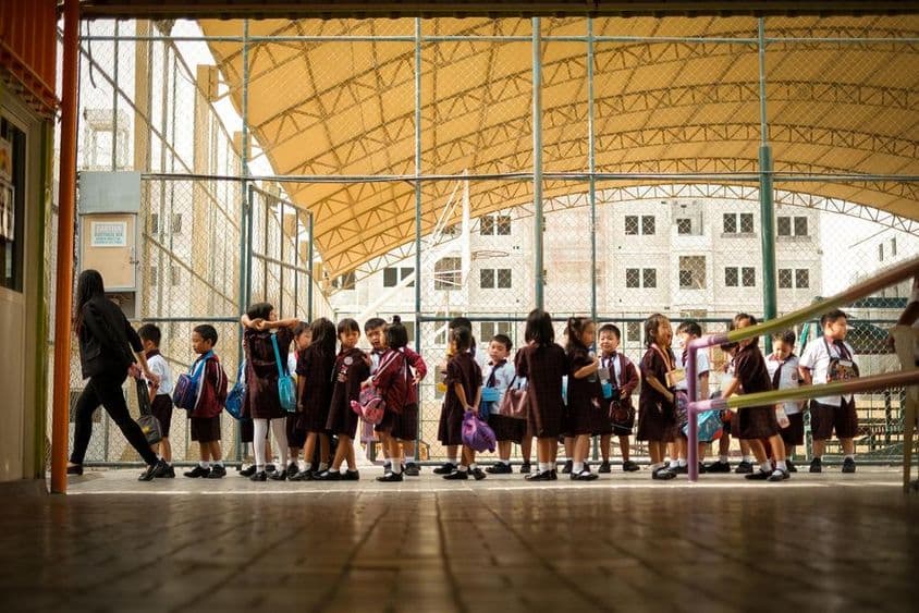 Kinder gehen über einen Schulcampus.
