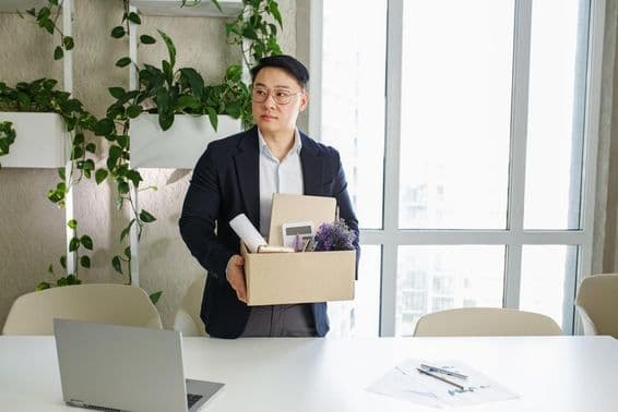 Ein Mann wird von seinem Arbeitsplatz entlassen und packt seine persönlichen Gegenstände in einen Karton.