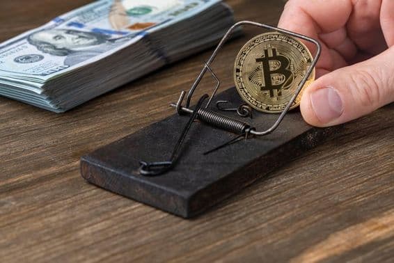 Kryptowährungs-Münzen Bitcoin in einer Mausefalle, gefangen mit 100 US-Dollar-Scheinen.