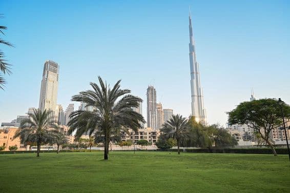 Dubai, Vereinigte Arabische Emirate, grüner Park im Wohngebiet mit Burj Khalifa im Hintergrund.