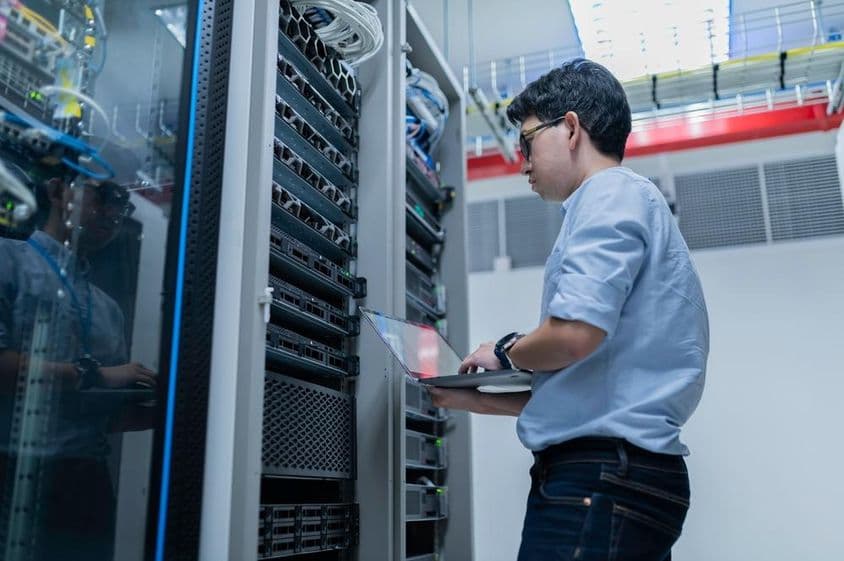 Männlicher Ingenieur arbeitet in einem modernen Datenzentrum-Serverraum.