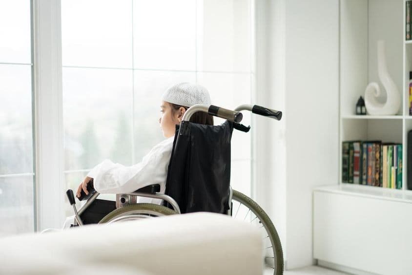 Ein Junge im Rollstuhl schaut durch ein Fenster.