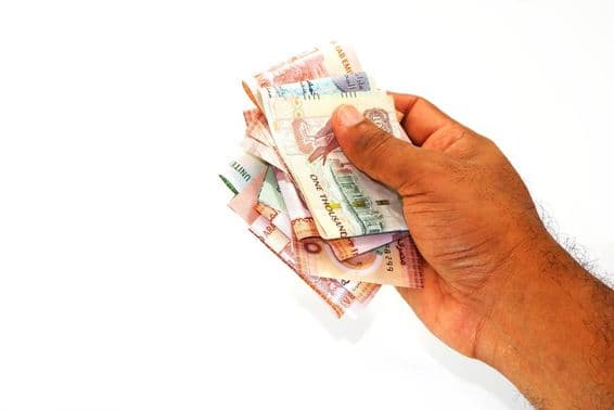 Dirham-Banknoten in der Hand eines Mannes.
