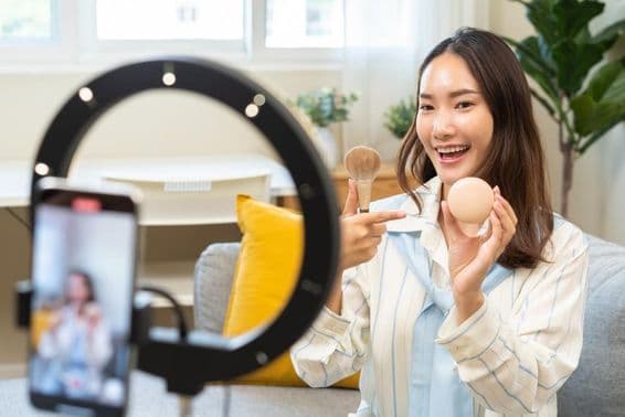 Junge Influencerin, die ein Smartphone benutzt und in einem Video-Podcast spricht.