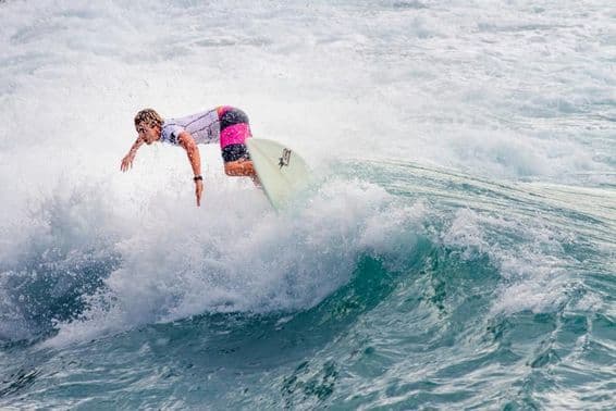 Junger Mann surft auf einer großen Welle.