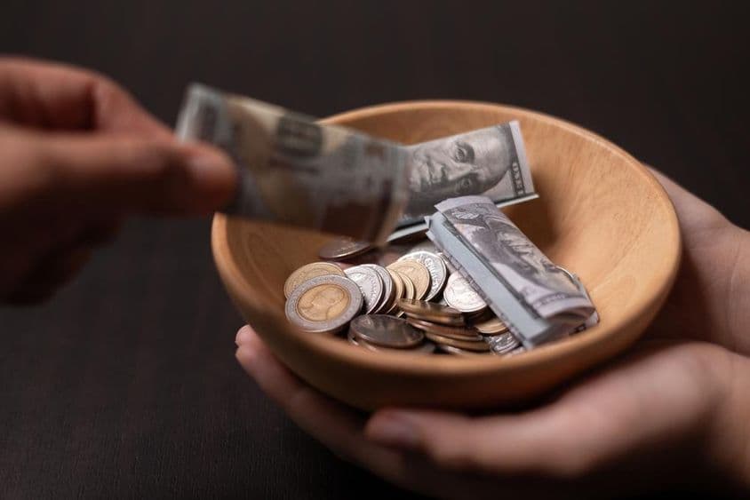 Spende wird in einem hölzernen Gefäß gesammelt.