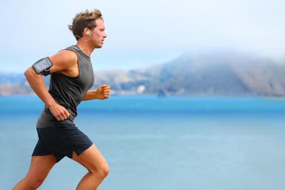 Männlicher Läufer hört Musik beim Joggen mit einem Smartphone.