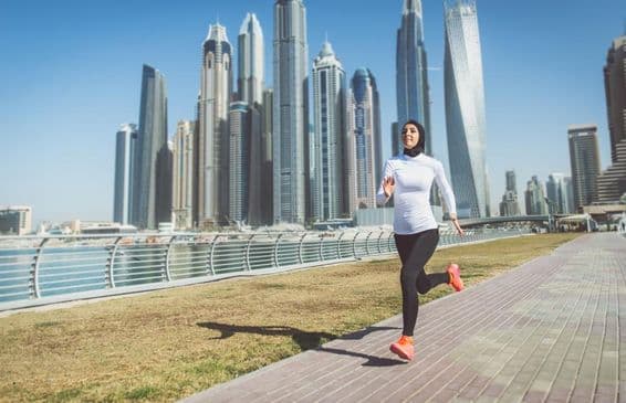 Arabische Frau läuft mit Wolkenkratzern im Hintergrund.
