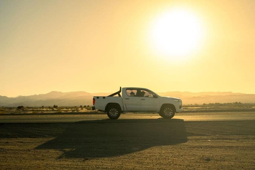 Weißes Pickup-Fahrzeug auf einem Ausflug auf dem Land, sonniger Tag bei Sonnenuntergang.