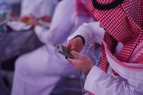 Arabischer Mann arbeitet an einem Mobiltelefon, liest oder schreibt eine Nachricht.