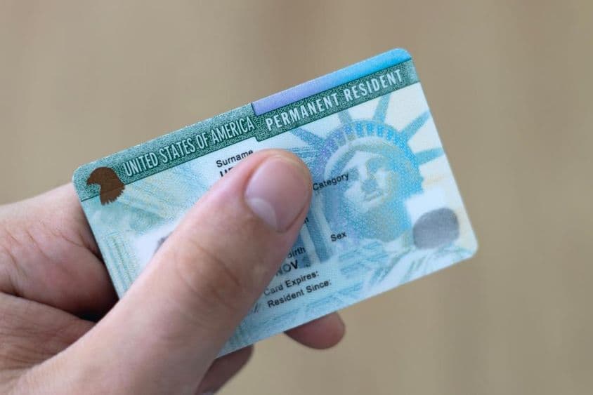 Ein dauerhafter Einwohner in den USA hält eine Green Card in der Hand.