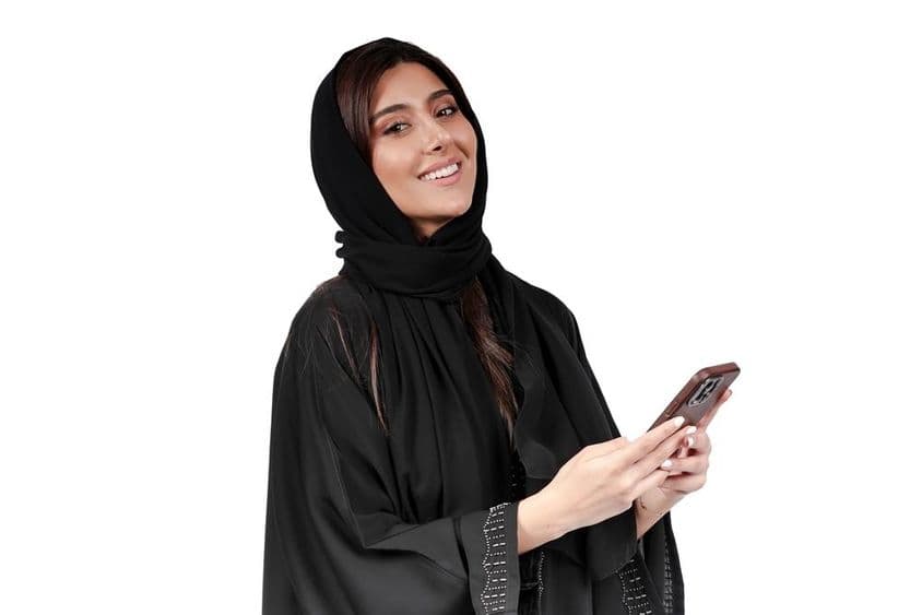 Emiratische Geschäftsfrau in arabischer Abaya, die am Mobiltelefon arbeitet.
