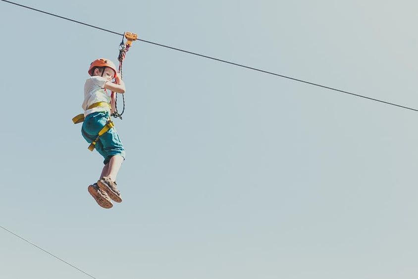 Junge, der an einem sonnigen Sommertag in einem Abenteuerpark klettert.