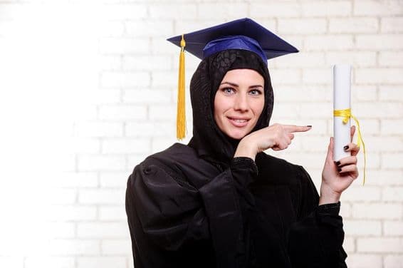 Glückliche muslimische Absolventin mit Diplom drinnen posierend.