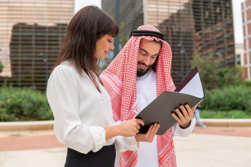 Geschäftsfrau bespricht Vertragsdetails mit arabischem männlichen Kunden.