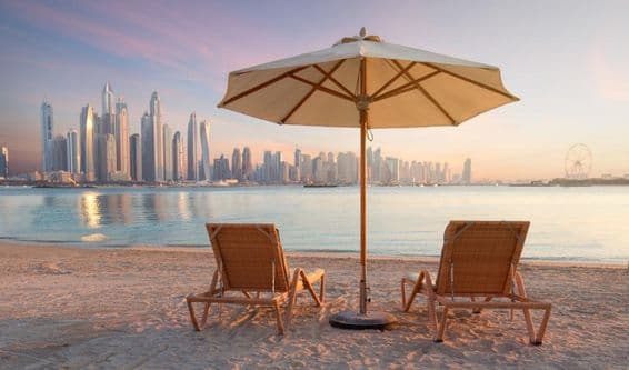 Schöner Strand in Dubai mit 2 Liegen und einem Sonnenschirm.