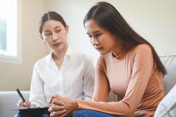 Traurige asiatische junge Frau in Beratung mit einem Psychologen.