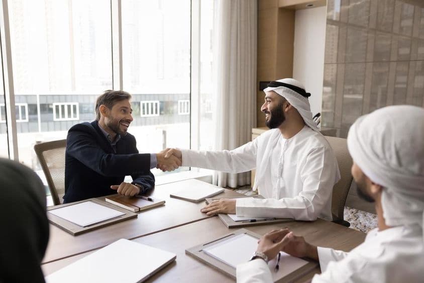 Multinationale Geschäftspartner schließen eine erfolgreiche Verhandlung mit einem Händedruck ab.