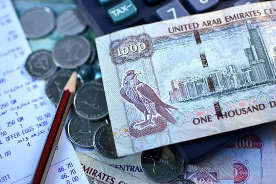 VAE 1000-Dirham-Geldschein und eine Handvoll Münzen.