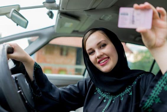 Glückliche muslimische Frau fährt ein Auto.