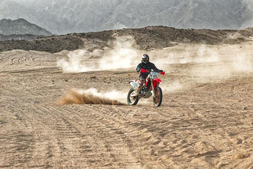 Motorradfahrer mit Helm fährt in der Wüste