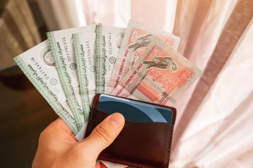 Dirham-Banknoten mit einer Geldbörse gehalten.