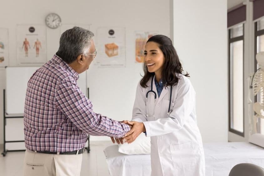Lächelnde junge Ärztin untersucht einen Patienten.