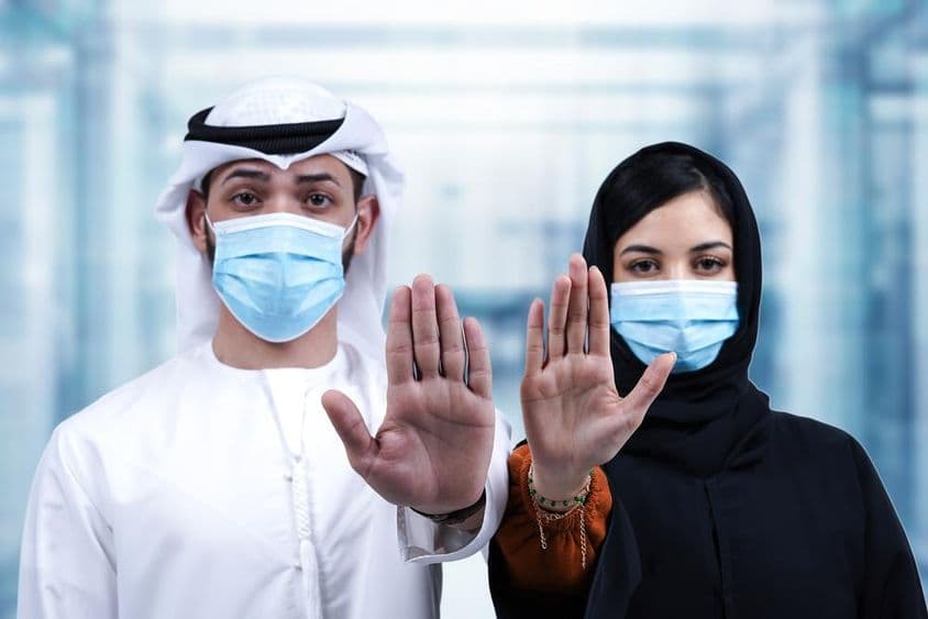 Arabischer Mann und Frau mit medizinischen Masken zeigen Stoppsignal.